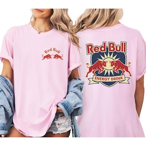 A woman wearing a pink t-shirt with the Red Bull logo and a graphic of two red bulls.