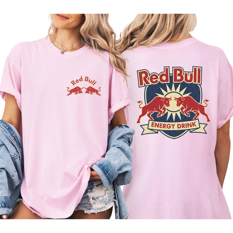 A woman wearing a pink t-shirt with the Red Bull logo and a graphic of two red bulls.