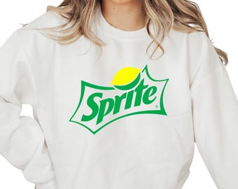 May include: White sweatshirt featuring the Sprite logo. The logo is green with a yellow lemon graphic. The word "Sprite" is in a green, stylized font. The sweatshirt is a casual, comfortable style.