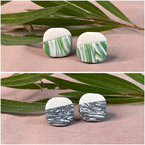 May include: Two pairs of ceramic earrings. The first pair is green and white with a marbled pattern. The second pair is black and white with a marbled pattern.