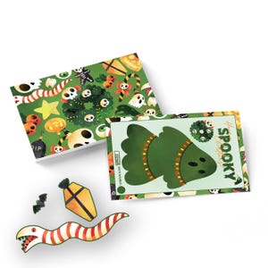 May include: A set of printable Halloween-themed cards featuring a spooky tree, a wreath, a snake, a coffin, and a bat. The cards are printed on white cardstock and have a green background with various Halloween-themed illustrations.