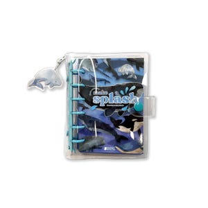 May include: A clear plastic planner with a blue and white whale design. The planner has a blue ring binder and a clear plastic cover. The planner has a whale charm attached to it. The planner has the text "make a splash" on the front.