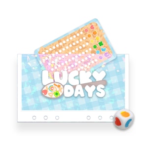 May include: A rectangular card with a light blue gingham pattern and the text LUCKY DAYS in white, featuring a spoon graphic with colourful cereal shapes. Above it, a smaller card shows a grid of white dots and cereal pieces. A white die is included.