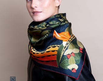 May include: A square silk scarf with a nature-inspired design. The scarf features a dark blue background with orange birds, green leaves, and red strawberries. The scarf has a red border and the text "LE CHÂLE BLEU - FRANCE".