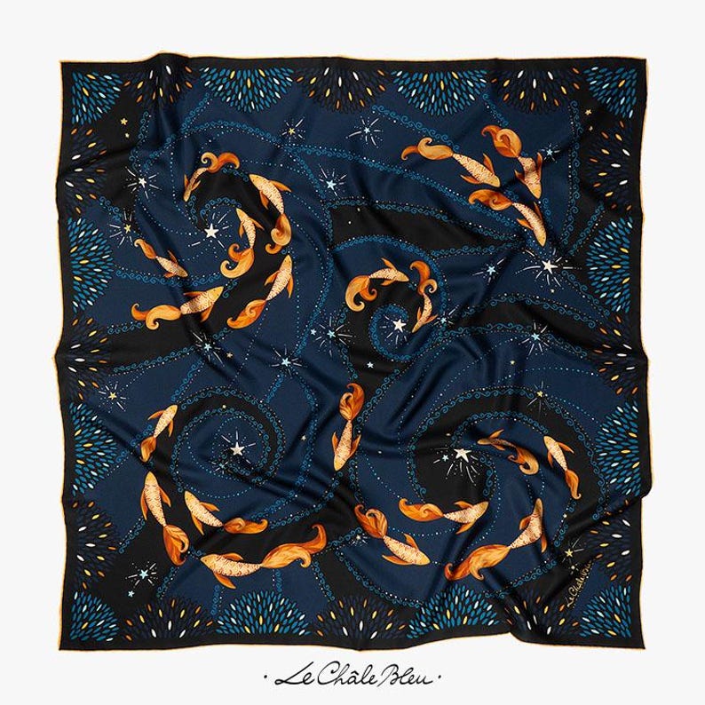 Puede incluir: Pa&ntilde;uelo cuadrado de seda con fondo azul marino que presenta un patr&oacute;n de peces naranjas, estrellas blancas y l&iacute;neas negras en espiral. El borde es negro con detalles azules y blancos. El texto "Le Chale Bleu" est&aacute; en la esquina inferior derecha.