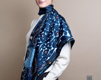 May include: A navy blue silk scarf with a white and blue tree branch design and red accents. The scarf is draped over a white sweater. The scarf has the text "Le Châle Bleu - France".
