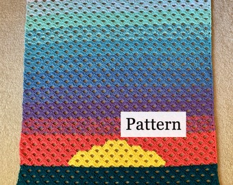 May include: A crochet blanket with a sunset design. The blanket is made with a variety of colors, including white, blue, purple, red, yellow, and green. The blanket has a "Pattern" label on it.
