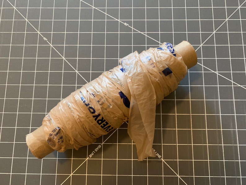 A roll of plastic yarn made from plastic grocery bags sits on a crafting surface.