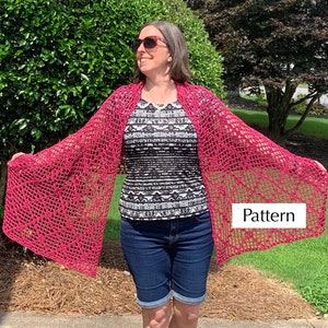 Puede incluir: Un chal de crochet rosa con un patrón de encaje. El chal está drapeado sobre los hombros de una persona. La palabra "Pattern" está escrita en el chal.