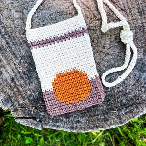 May include: A crocheted beige, brown, and orange crossbody bag with a long strap. The bag has a geometric design with a circle in the center.