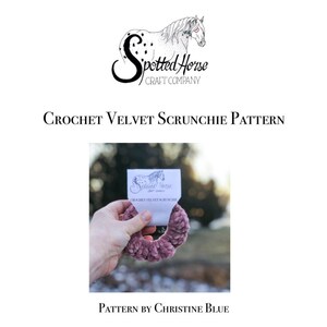 May include: A close-up of a dusty rose velvet scrunchie with a white tag that reads "Spotted Horse Craft Company" and "Crochet Velvet Scrunchie". The scrunchie is held in a hand against a blurred background.