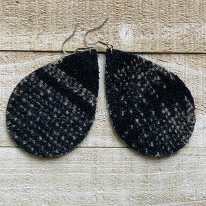 May include: A pair of black and white teardrop-shaped earrings with a textured fabric design.