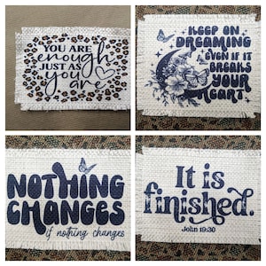 May include: Four burlap patches with inspirational quotes printed in black. The first patch has a leopard print background and says "You are enough just as you are". The second patch has a crescent moon with stars and butterflies and says "Keep on dreaming even if it breaks your heart". The third patch says "Nothing changes if nothing changes". The fourth patch says "It is finished. John 19:30".