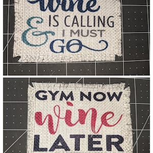 May include: Two burlap signs with frayed edges. The top sign reads "wine & I must go" in blue and teal lettering. The bottom sign reads "Gym Now Wine Later" in black and red lettering.