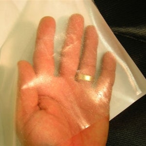 May include: A clear, translucent sheet of plastic material. The sheet is held up to a light source, revealing its texture and translucency.