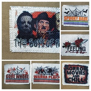 May include: A set of 10 burlap patches with various horror movie themes. The patches feature images of iconic horror movie characters, including Michael Myers, Freddy Krueger, and Jason Voorhees. The patches also include text such as "The Boys of Fall", "Spooky Babe", "Gore Whore", "Wanna Play?", and "Horror Movies and Chill".