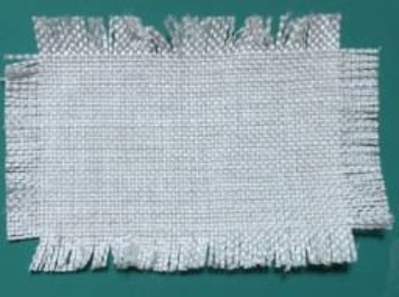 May include: A white woven fabric with a frayed edge.