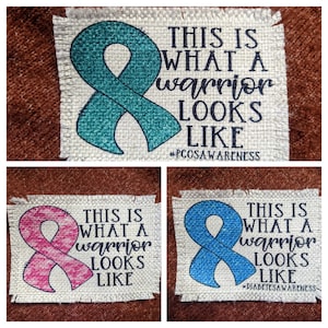 May include: Three fabric patches with a ribbon design and text. The first patch is teal with the text "THIS IS WHAT A warrior LOOKS LIKE #PCOSAWARENESS". The second patch is pink with the text "THIS IS WHAT A warrior LOOKS LIKE". The third patch is blue with the text "THIS IS WHAT A warrior LOOKS LIKE #DIABETESAWARENESS".