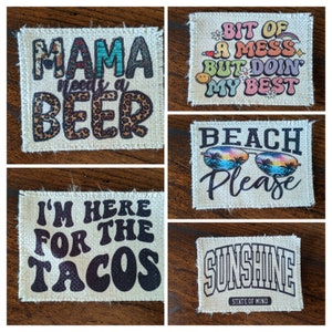 May include: Five different burlap patches with various sayings. The patches are all rectangular and have a frayed edge. The sayings are: "Mama needs a beer", "Bit of a mess but doin my best", "Beach Please", "I'm here for the tacos", and "Sunshine State of Mind".