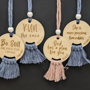 May include: Four wooden circle ornaments with tassels, each with a different inspirational quote and scripture reference. The quotes are "Run the race", "Be Still and Know That I Am God", "God Has a Plan for You", and "She is More Precious Than Rubies".