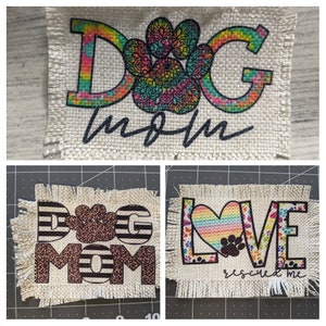 May include: Three burlap patches with colorful designs and text. The first patch says "DOG mom" with a rainbow paw print. The second patch says "DOG MOM" with a black and white striped background and a leopard print paw print. The third patch says "LOVE rescued me" with a rainbow heart and paw prints.