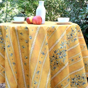 Könnte beinhalten: Eine runde gelbe und weiße gestreifte Tischdecke mit einem Muster aus Olivenzweigen und Oliven. Die Tischdecke hat einen Durchmesser von etwa 150 cm.