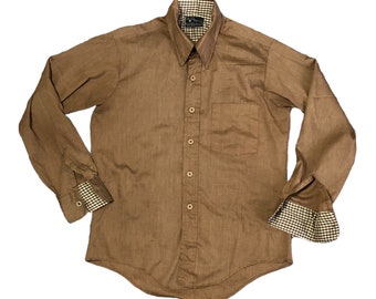 Puede incluir: Una camisa marrón de manga larga con botones y un patrón a cuadros en el cuello y los puños.