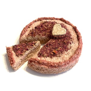 May include: A pink cake with a heart-shaped decoration on top. A slice of the cake is missing.