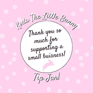 Op de afbeelding: Een roze achtergrond met witte stippen en een witte cirkel met de tekst "Koda The Little Bunny" in zwarte, cursieve letters. De cirkel bevat ook de tekst "Thank you so much for supporting a small business!" in zwarte letters. Een roze konijnen silhouet bevindt zich onderaan de cirkel. De tekst "Tip Jar!" staat onder de cirkel in zwarte, cursieve letters.