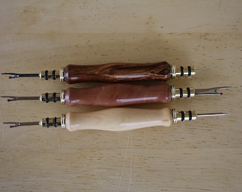 Könnte beinhalten: Drei Holz-Faden-Schneider mit unterschiedlich farbigen Griffen. Die Griffe sind aus Holz mit natürlicher Maserung. Die Schneider haben eine Klinge aus Metall und einen schwarzen Gummigriff.