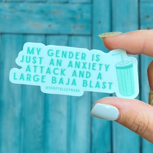 May include: A teal blue sticker with the text "My gender is just an anxiety attack and a large Baja Blast" and the social media handle "@shoptalleymark". The sticker features a cartoon illustration of a blue and white cup with a straw.
