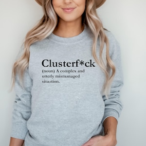 May include: Grey sweatshirt with the word "Clusterf*ck" defined as "A complex and utterly mismanaged situation."