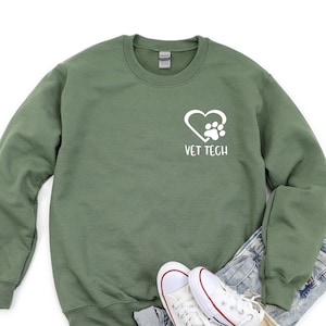Op de afbeelding: Een groen sweatshirt met een wit hart en een pootprintontwerp en de tekst "VET TECH".