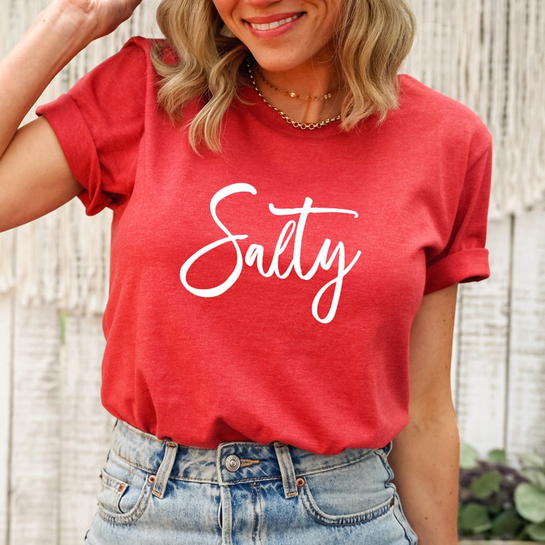 May include: Red t-shirt with the word "Salty" written in white cursive lettering.