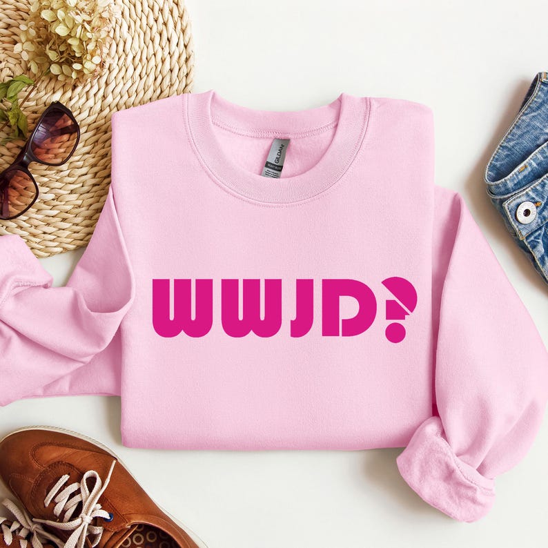 May include: Pink sweatshirt with the text "WWJD?" in bold pink letters.
