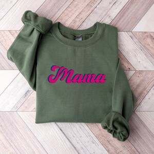 May include: A green sweatshirt with the word "Mama" in pink and blue lettering.