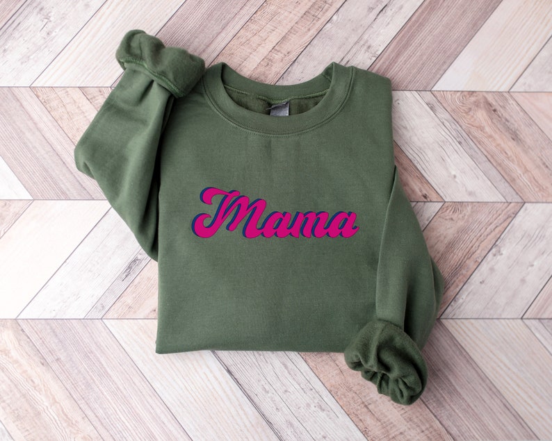 May include: A green sweatshirt with the word "Mama" in pink and blue lettering.