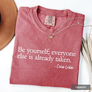 A crimson Comfort Colors t-shirt printed with the quote "Be yourself; everyone else is already taken. - Oscar Wilde" in white lettering.