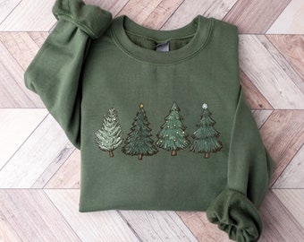 May include: A green sweatshirt with a graphic of five Christmas trees with ornaments and a star on top. The trees are in a row and are different sizes.