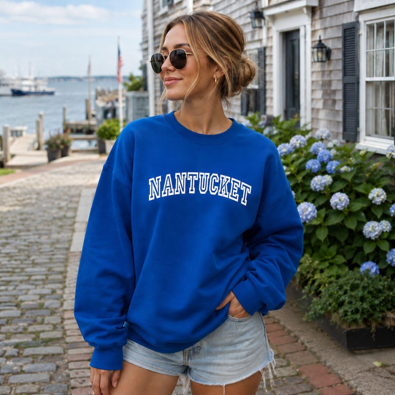 Puede incluir: Una sudadera de cuello redondo en color azul real con la palabra NANTUCKET impresa en letras may&uacute;sculas blancas en el pecho con una tipograf&iacute;a de estilo universitario. La prenda tiene mangas largas, cuello acanalado y un corte holgado.