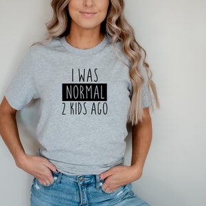 May include: A gray t-shirt with the text "I was normal 2 kids ago" printed in black.