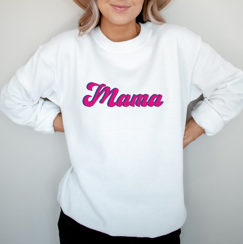 May include: White sweatshirt with a pink and blue retro-style "Mama" graphic.