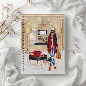 May include: Spiral-bound notebook with a fashion illustration. The cover features a woman in a red coat, jeans, and sunglasses, standing in a luxurious room. The background includes a chandelier, lamps, and a marble-like design. Text on the cover reads "Your name here."