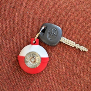 May include: A red and white round keychain with the words "Believe" and "Always" printed on it. The keychain is attached to a black car key with a silver key blade.