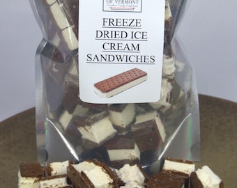 May include: A clear plastic bag filled with freeze-dried ice cream sandwiches. The bag is labeled "Alderman's of Vermont Freeze Dried Ice Cream Sandwiches". The ice cream sandwiches are in bite-sized pieces and are scattered on a brown surface.