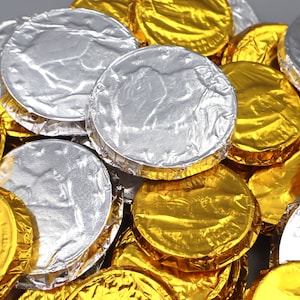 May include: A pile of gold and silver foil-wrapped chocolate coins. The coins are arranged in a random pattern.