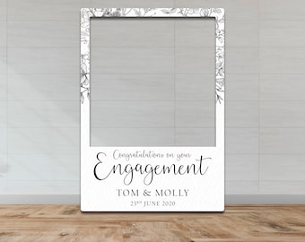 Puede incluir: Marco blanco para cabina de fotos con diseño floral y el texto "Felicidades por su compromiso TOM & MOLLY 23 de junio de 2020".