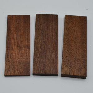 May include: Three rectangular pieces of wood, each with a different shade of brown. The wood has a natural grain pattern.