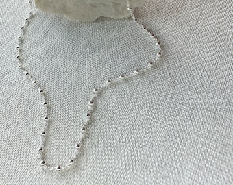 May include: A silver chain necklace with small round beads.