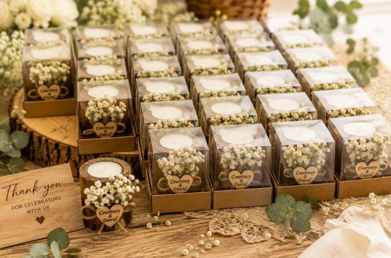 Pu&ograve; includere: Una collezione di piccoli portacandele in legno con lumini bianchi, ciascuno racchiuso in una scatola quadrata trasparente. Ogni portacandele &egrave; decorato con fiori bianchi di gipsofila e un'etichetta in legno a forma di cuore.